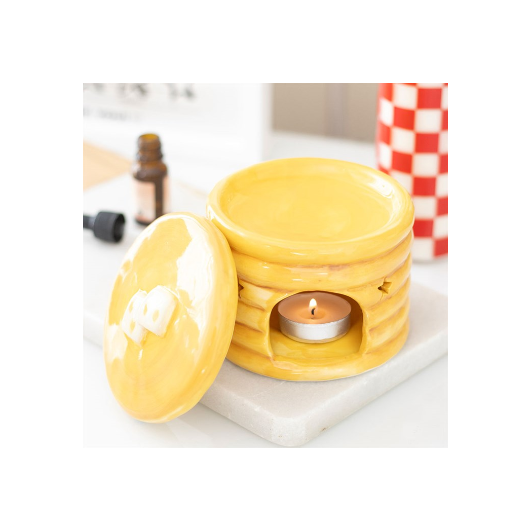 Yellow pancake-stack ceramic oil burner with syrup glaze, star cutouts, and tealight inside.