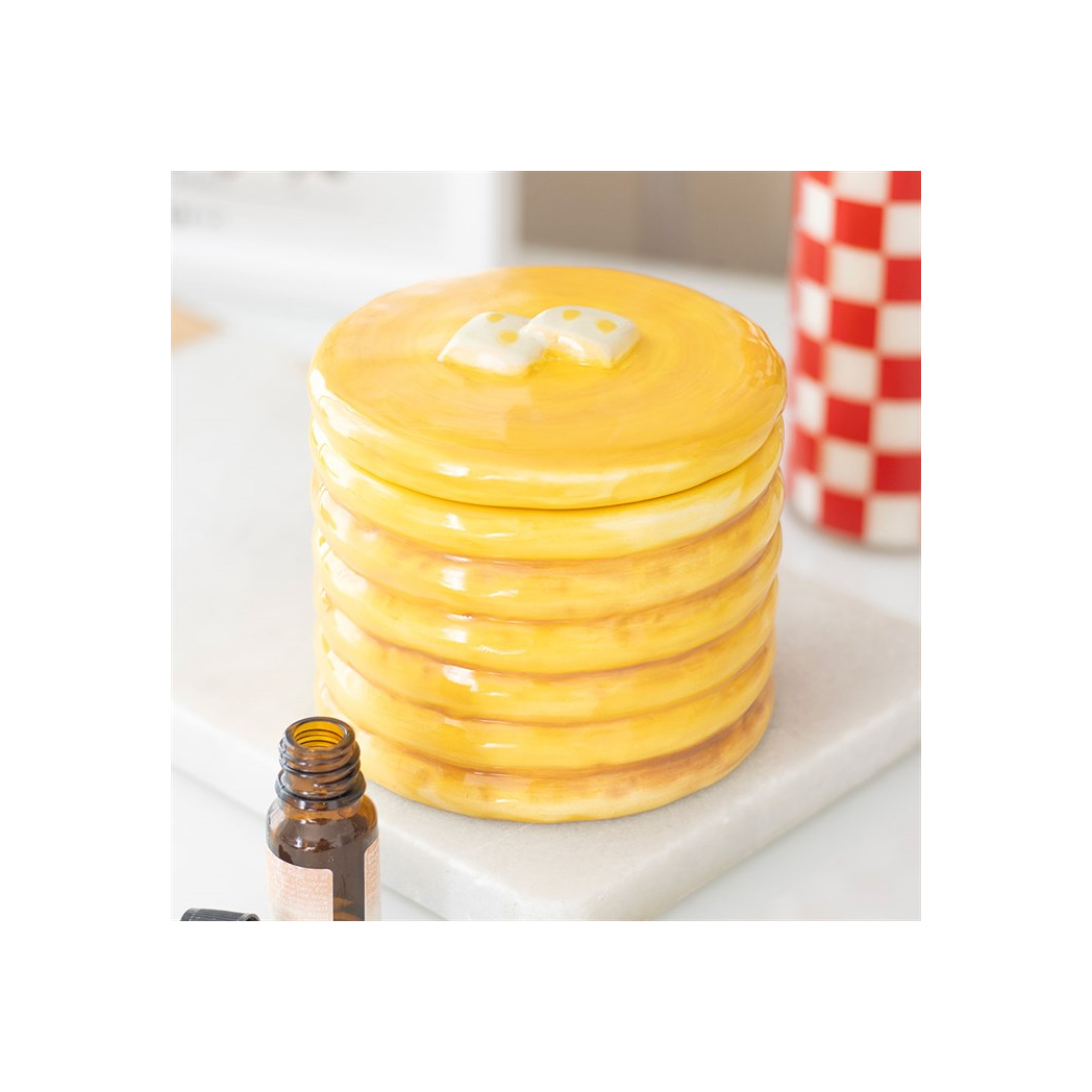 Pancake-stack ceramic oil burner with glossy yellow glaze and syrup finish on a marble surface, oil bottle