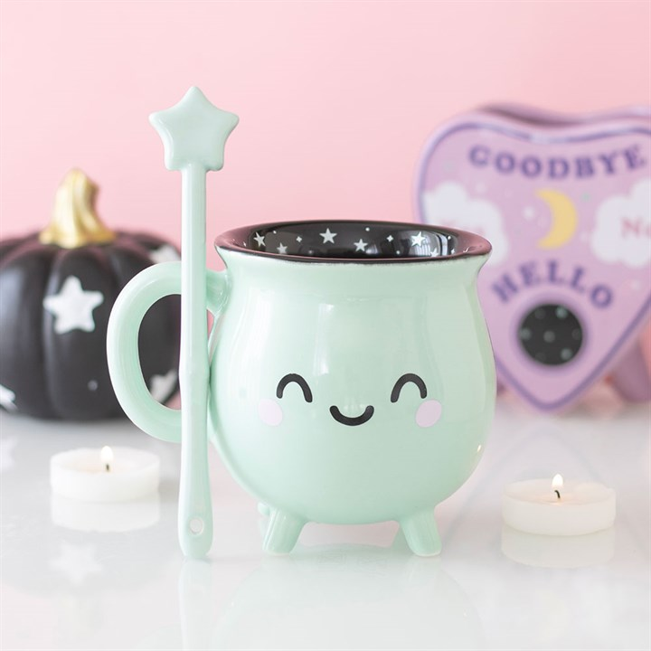 Mint green mug with star design, spoon, and candles on a pink background