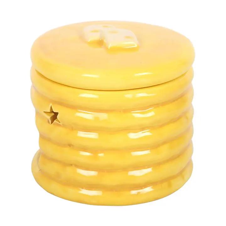 Pancake-stack ceramic oil burner in glossy yellow glaze with star cutouts, adds cozy fragrance to a shelf.