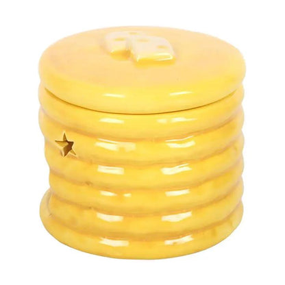 Pancake-stack ceramic oil burner in glossy yellow glaze with star cutouts, adds cozy fragrance to a shelf.