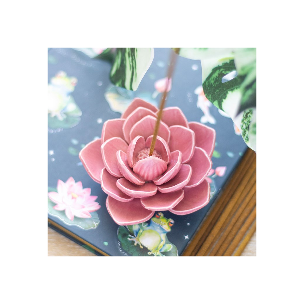 Pink flower-shaped incense burner on a decorative card with floral design