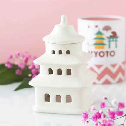 White ceramic lantern with pink flowers and a blurred product in the background